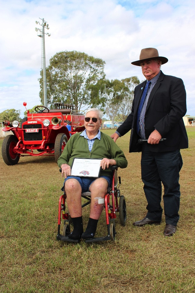 Bogan Shire Mayor Glen Neill presents Keith White with a certificate of appreciation for his efforts to have the Garford engine restored.